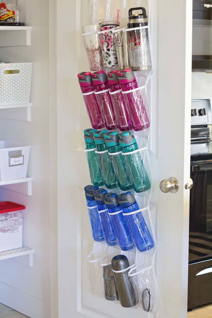 clear plastic hanging storage holding water bottles on inside of pantry door