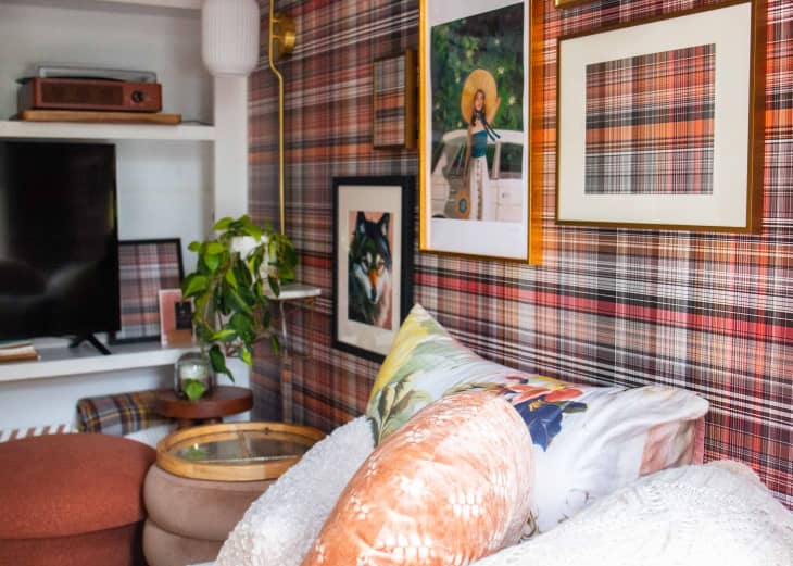 Framed pieces of art on a plaid wallpapered wall.