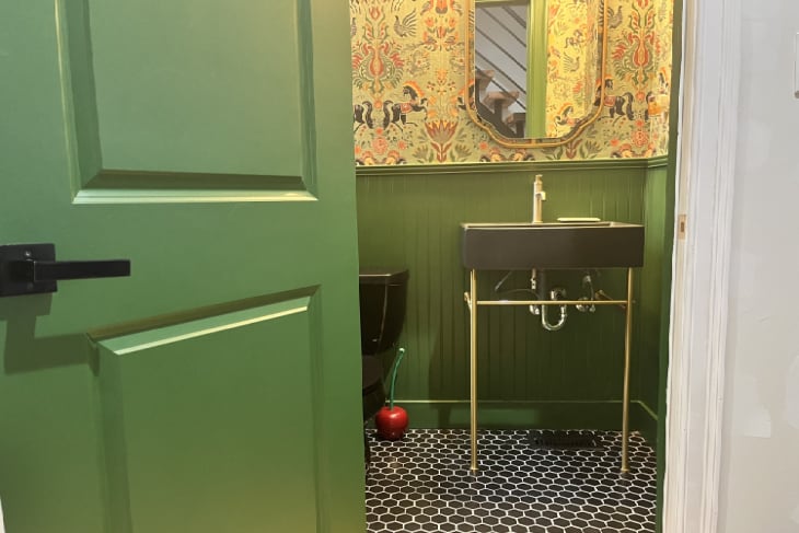 Green bathroom with black sink, toilet, and hex tile floors