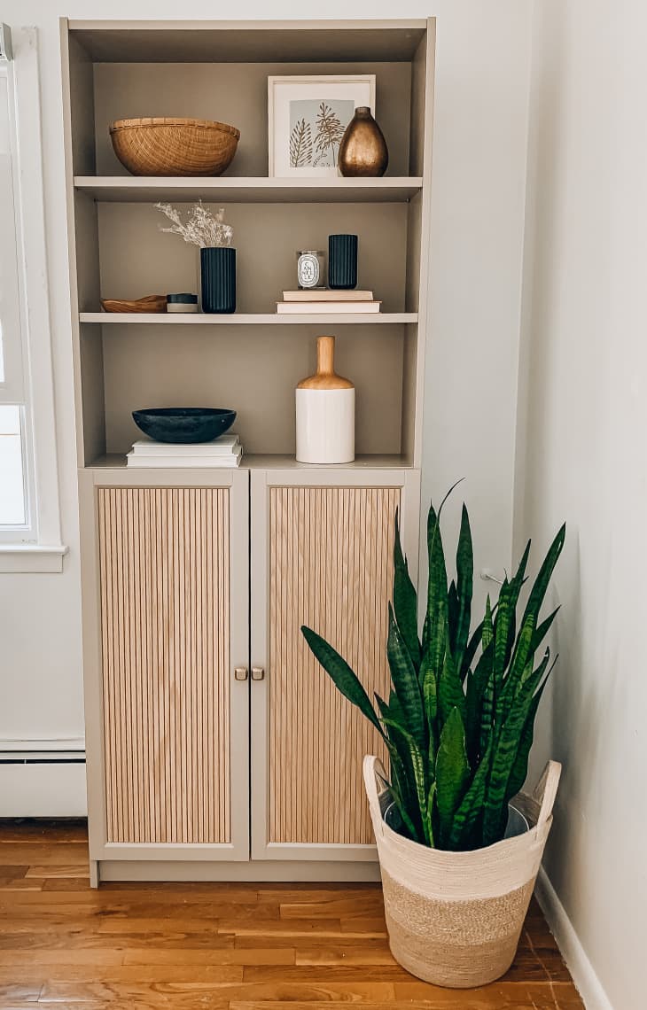 Tan bookshelf with a cabinet next to a plant