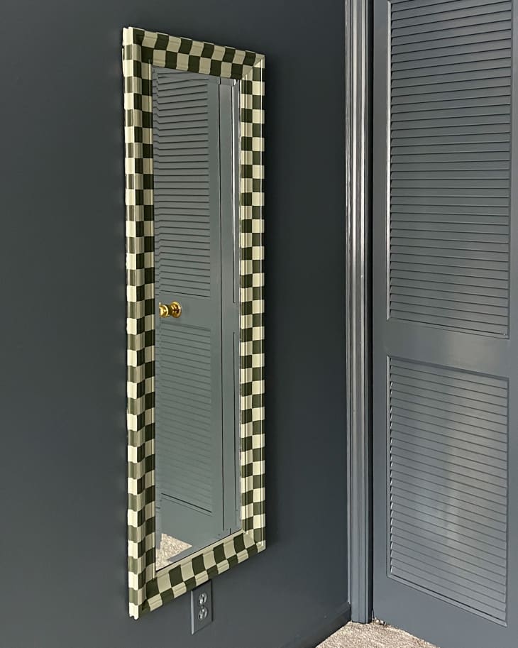 full length mirror with dark and light green checkered frame mounted on gray wall