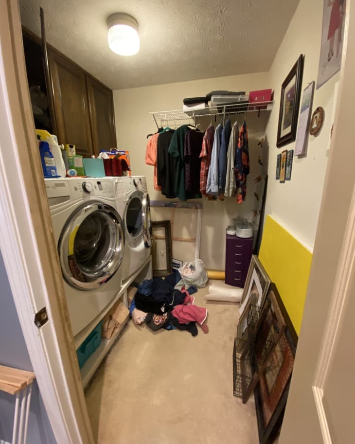 Wood cabinets with washer and dryer below, messy top with detergent and cleaning supplies everywhere, hanging clothes on rack, pile of clothes on floor