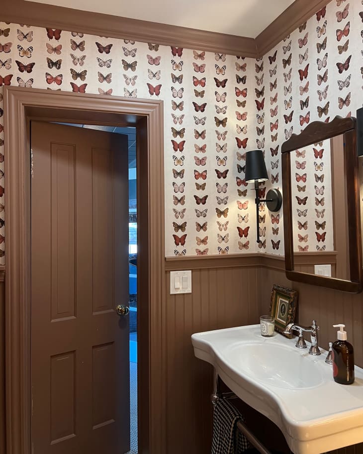 Brown painted wainscoting and trim in bathroom with butterfly wallpaper.