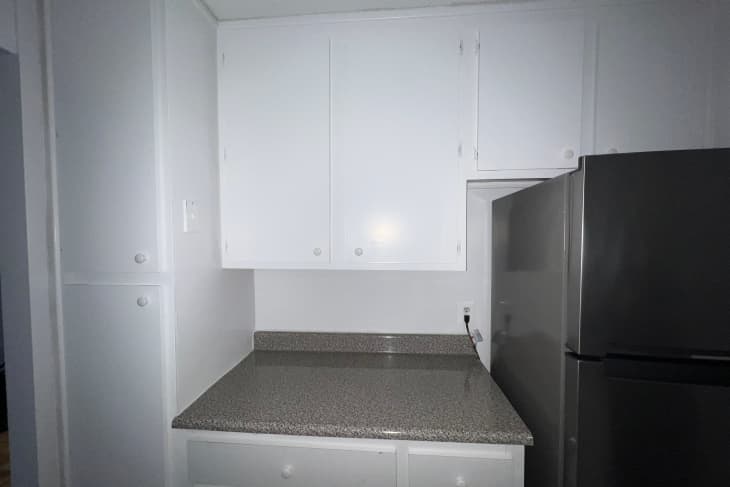 A basic white apartment kitchen before a peel-and-stick renovation.