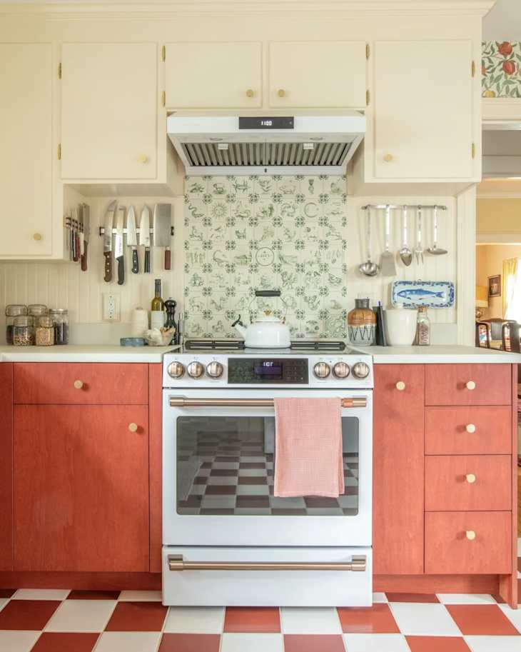 Modern kitchen with white stove, red checkered floor, floral backsplash, and wooden cabinets.