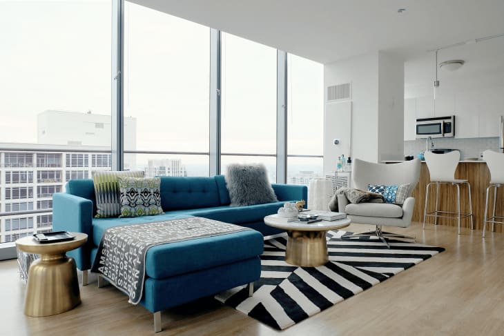 Living room in neutral colors aside from blue sofa and metallic accents
