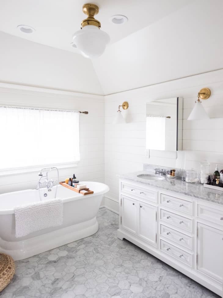 A white bathroom with gray tile flooring.