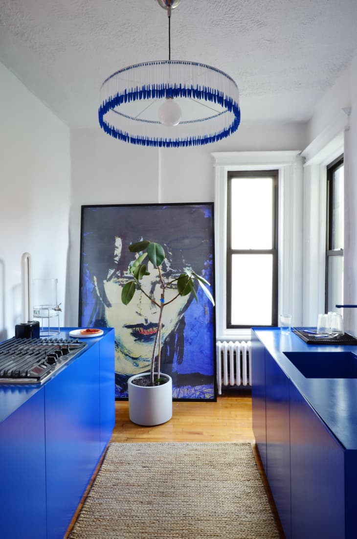 Bright blue cabinets in a modern kitchen with a round pendant light with blue fringe