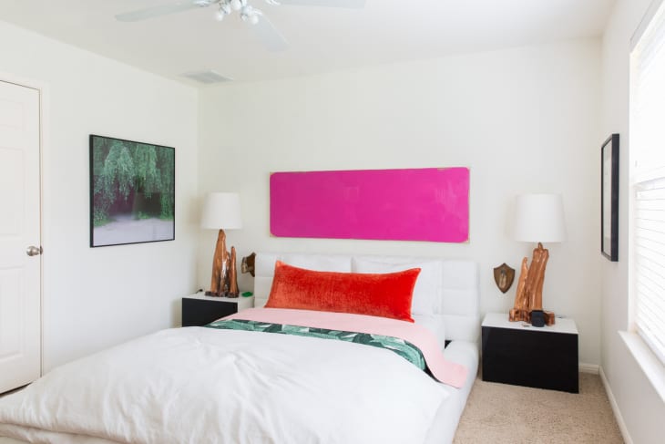 a mostly white bedroom with a wall-mounted pink headboard