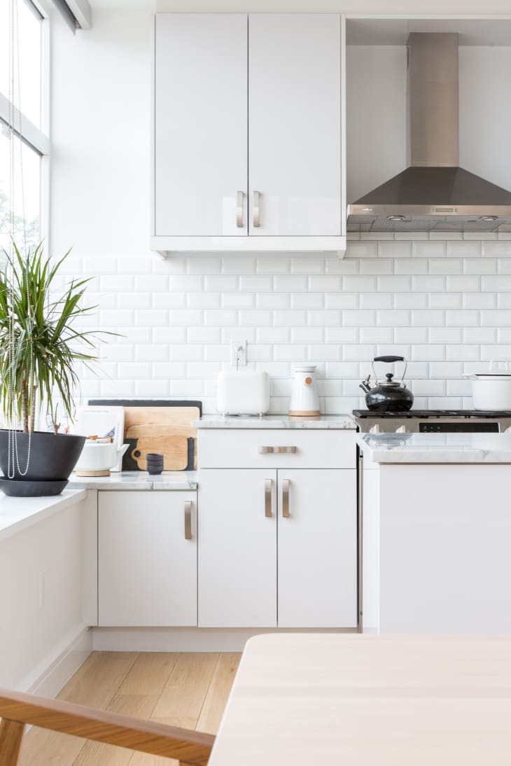 A neutral kitchen with white subway tiles and a green plant by the window