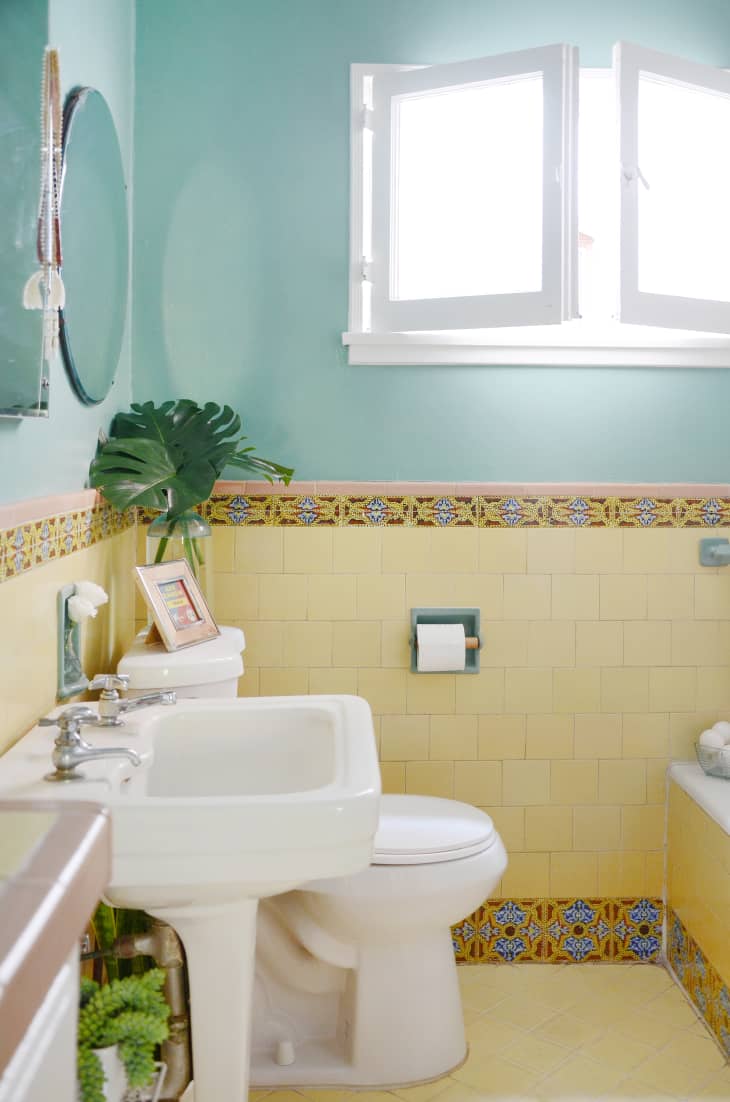A half-tiled bathroom with blue walls and yellow tile.