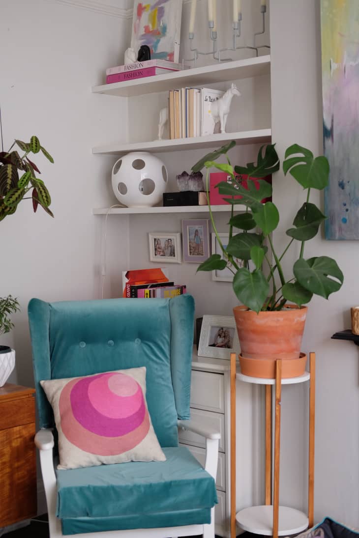 A blue chair with a decorative pillow beside a houseplant.