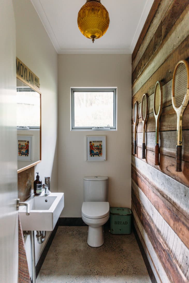 Half bath with rustic wood plank walls and orange pendant light