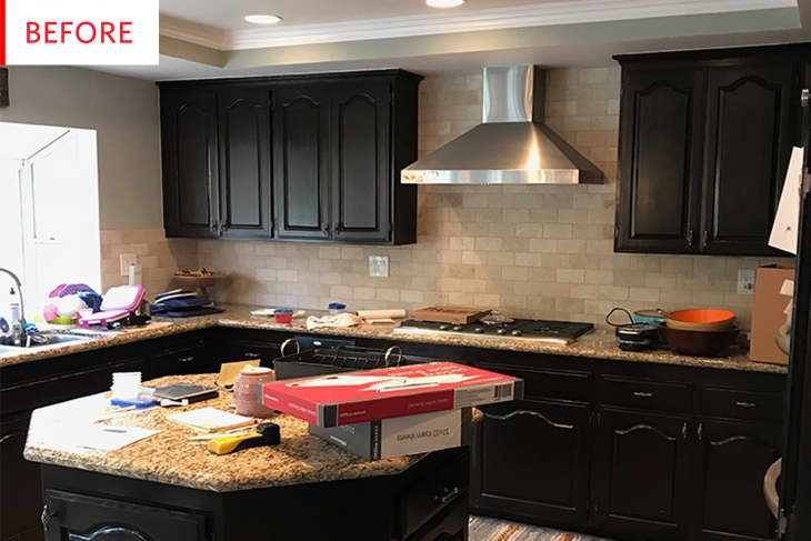 Before: Black upper and lower cabinets in a kitchen with a stainless steel range hood and tan tile on the walls