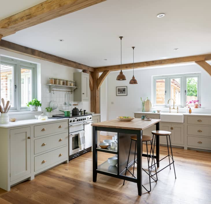 A white kitchen with wood floors and wood beams