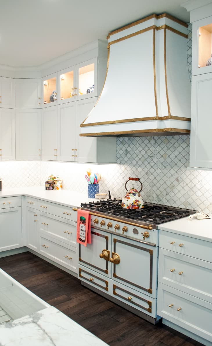 a white kitchen with gold hardware and accents