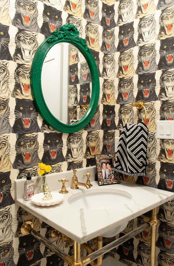 Half bathroom with tiger wallpaper and green mirror frame