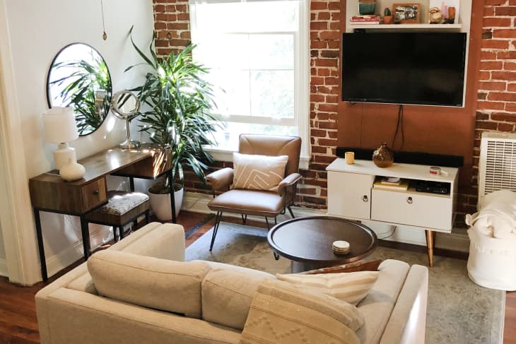 Small living room with sofa, tables, desk, and plants