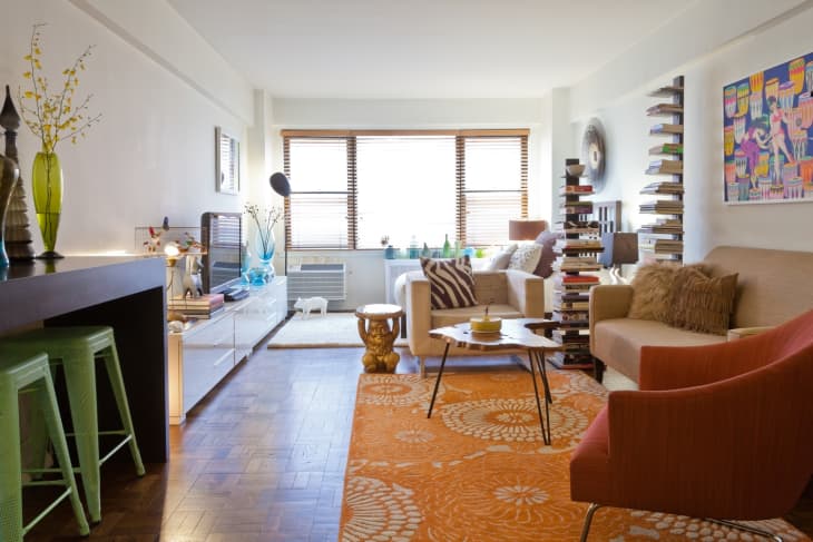 Colorful modern studio apartment with orange rug and white walls
