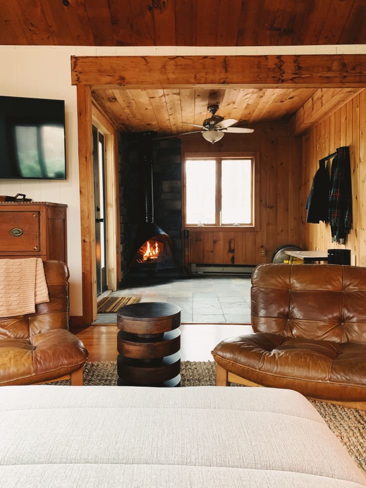 Wood paneled cabin room with black fireplace and brown leather chair