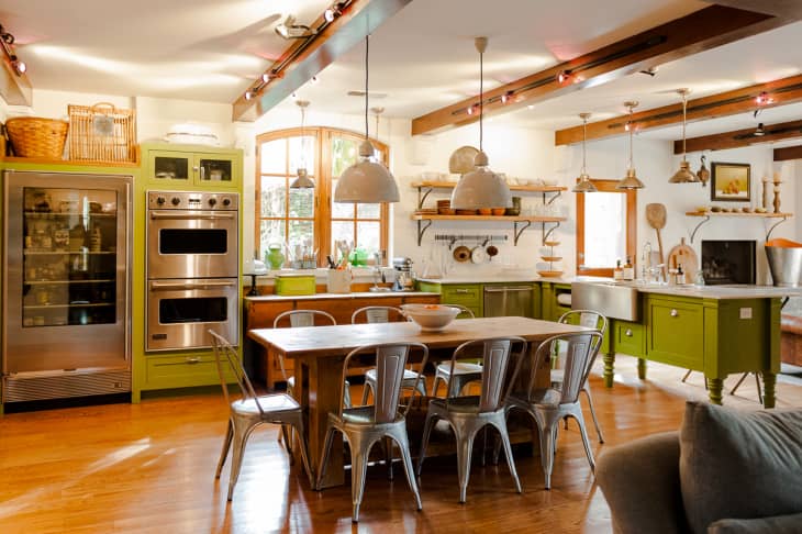 An industrial home kitchen with wooden cabinets painted chartreuse and stainless steel appliances