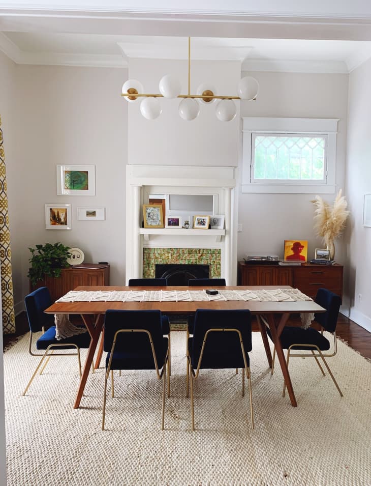 Eclectic dining room with West Elm globe chandelier, velvet blue upholstered dining chairs, and mid-century modern inspired wood furniture