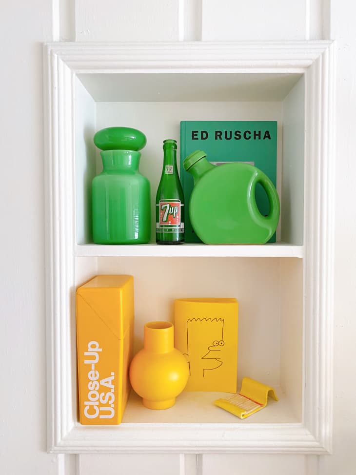 Build-in white shelves with green vintage accessories on one shelf and yellow vintage accessories on the other