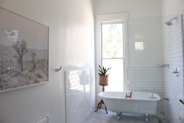 All white traditional bathroom with a clawfoot tub inside of a tiled shower
