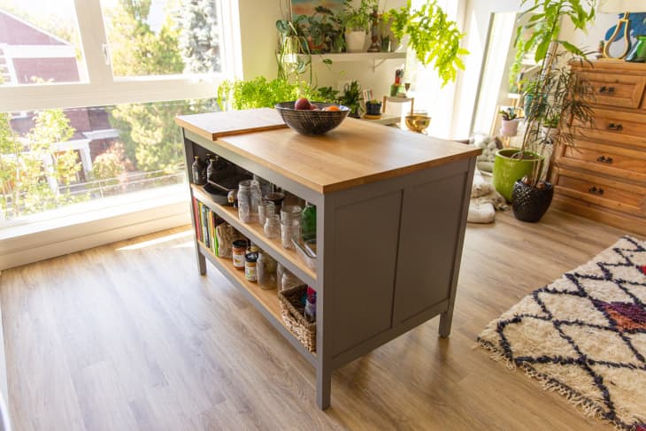 Modern IKEA kitchen island with oak top and shelves filled with jars and kitchen tools