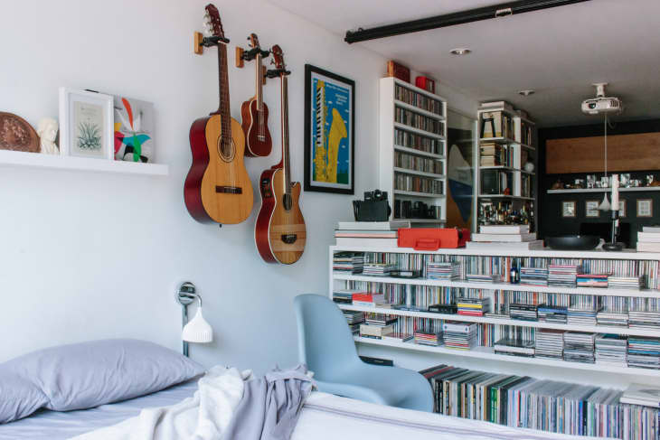 Bedroom with guitars hanging on wall and music and media on shelf