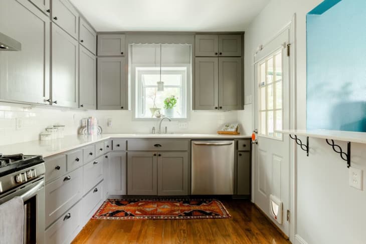 Kitchen with gray cabinets, hardwood floors, and white backsplash and counters