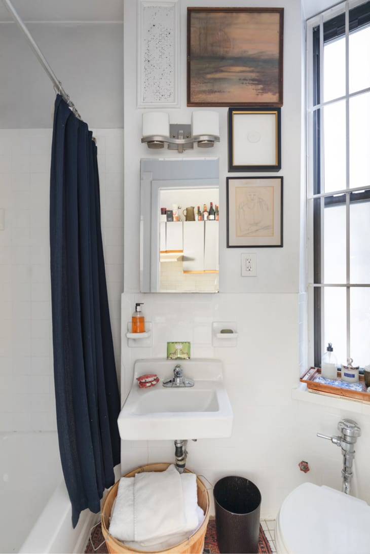 Bright bathroom with window, small sink, and navy shower curtain