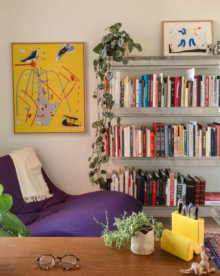 Bookshelf with colorful books next to purple chair and yellow painting