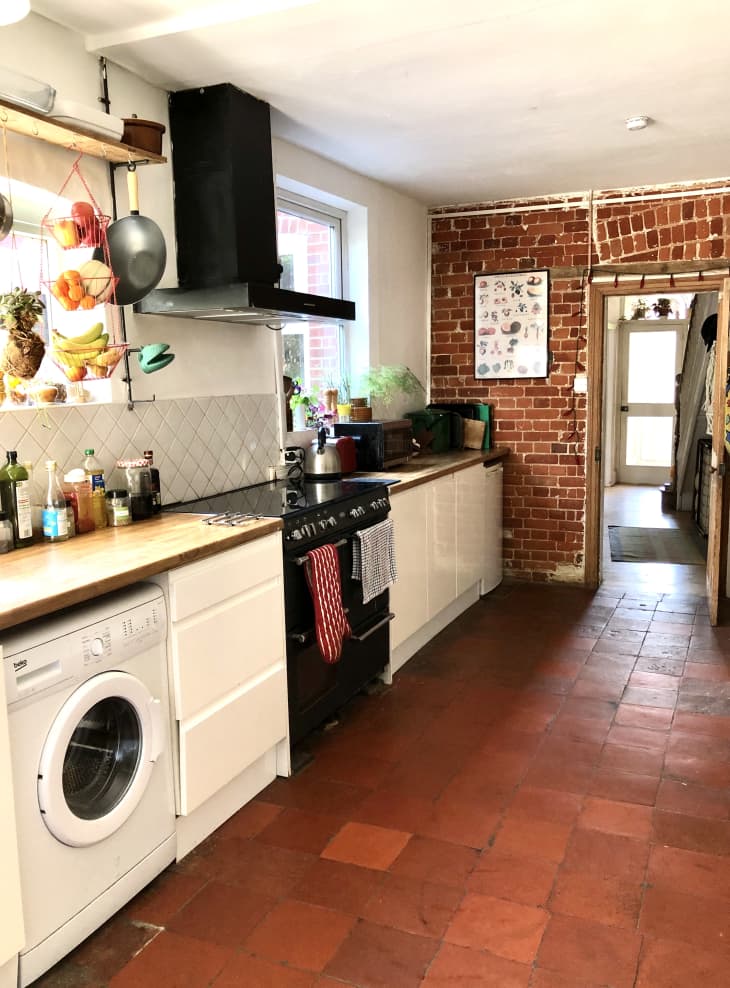 Galley kitchen with exposed brick wall and red tile floors