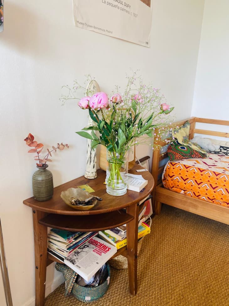 Half-circle side table holding flowers and stacks of books