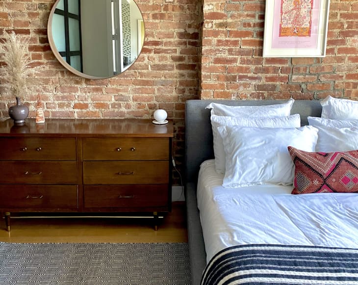 Bedroom with exposed brick and circular mirror