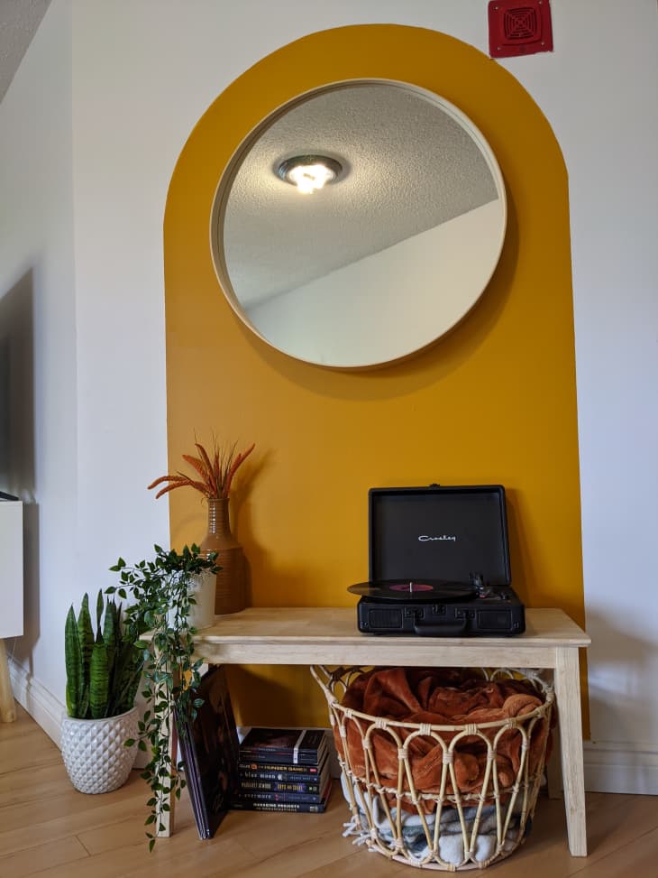 Circular mirror centered in gold painted arch shape in hallway
