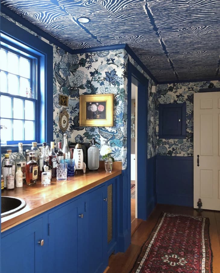 Kitchen with blue cabinets, wallpaper, and ceiling