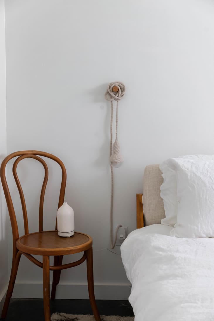 Small wooden Thonet-shaped chair next to bed with white linens