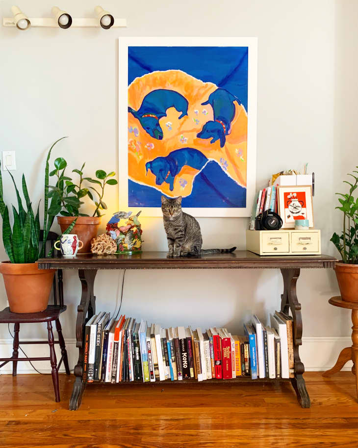 Blue puppy artwork above accent table with books on bottom shelf