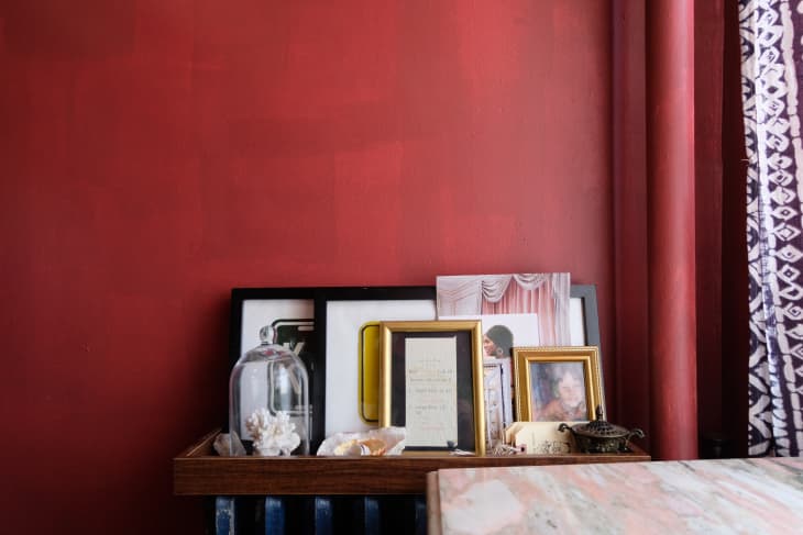 Frames and trinkets on shelf against red wall