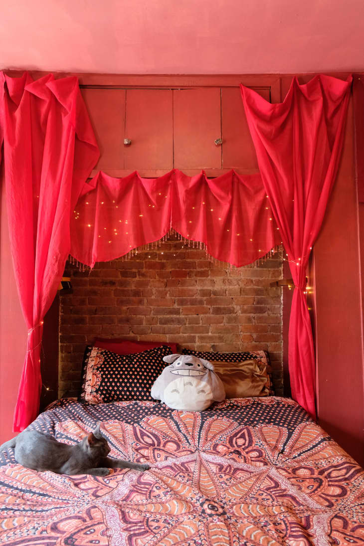 Bed in front of brick wall with red canopy hanging above