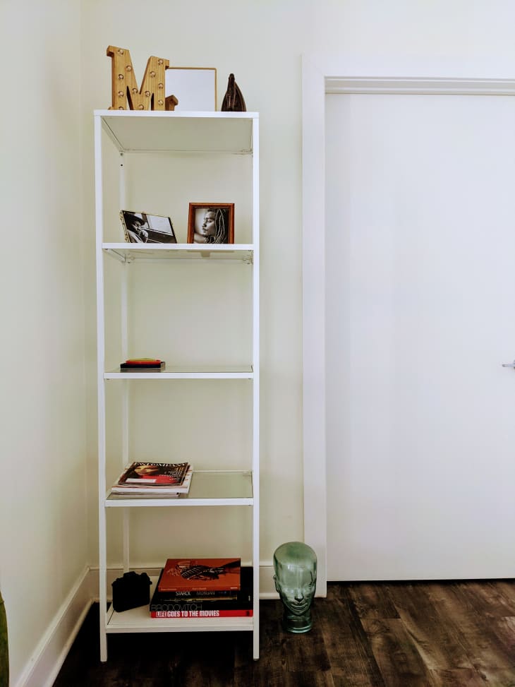 Sleek white shelf holding books and frames