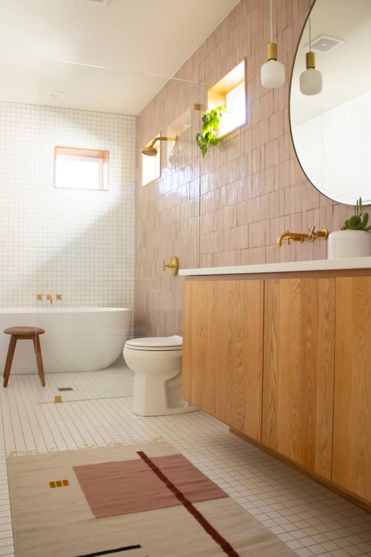 浴室配有腮红彩色瓷砖，几何地毯和圆形镜