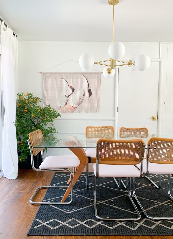 Dining area with retro caned chairs, white walls, and black and white diamond-pattern rug