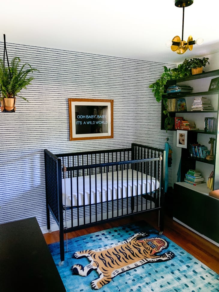 Nursery with sleek black crib and tiger rug