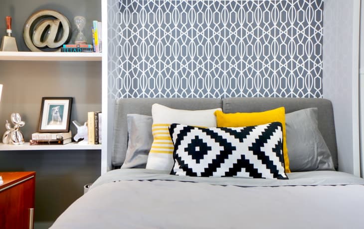 Close-up of bed with gray bedding and yellow throw pillows