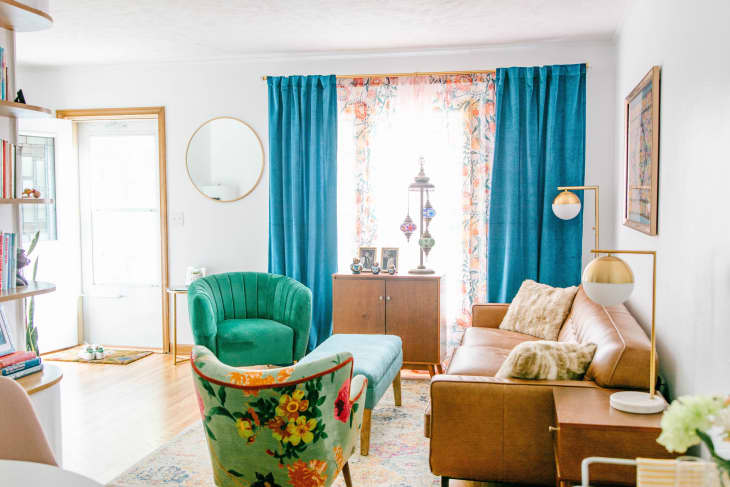 Bright living room with teal curtains, leather sofa, and green accent chairs