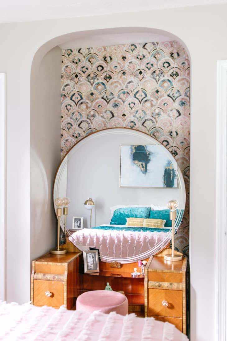 Vanity with circular mirror in wallpapered alcove