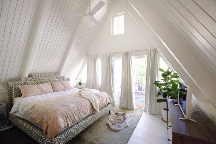 Primary bedroom painted white in A-frame shaped house